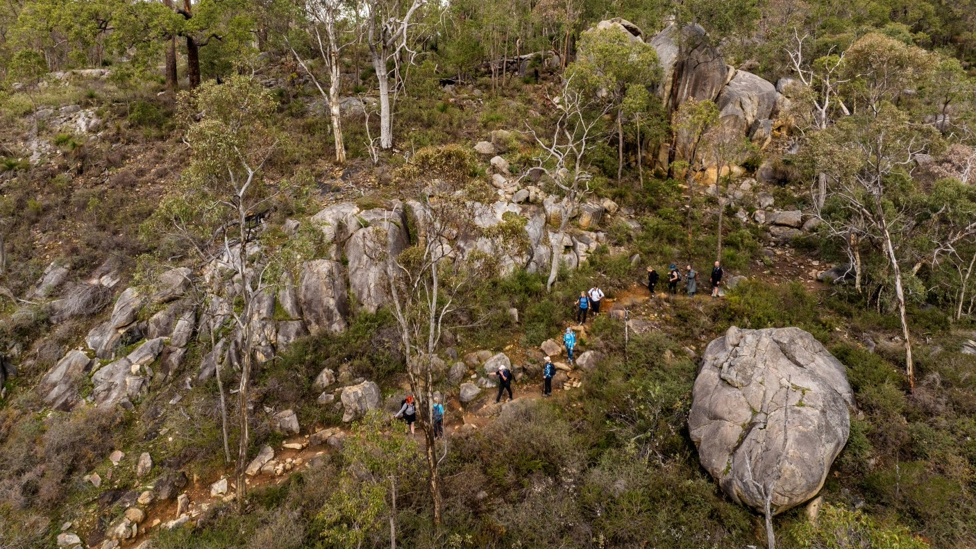 An aerial view of a few people hiking on a mountain track.